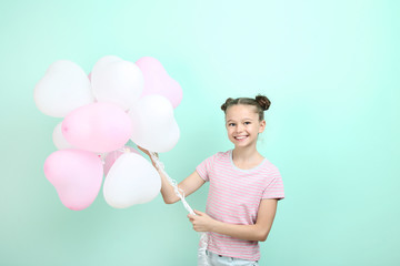 Beautiful young girl with balloons on mint background