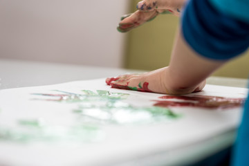 Toddler child making colourfull palm prints