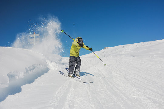 Active skier in bright yellow sportswear riding down the mountains