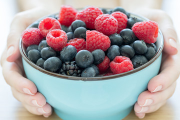 Bowl of fresh organic berries in hands as healthy breakfast option