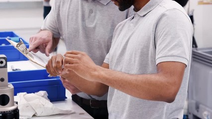 Engineer And Male Apprentice Measuring Components In Hi Tech Engineering Plant