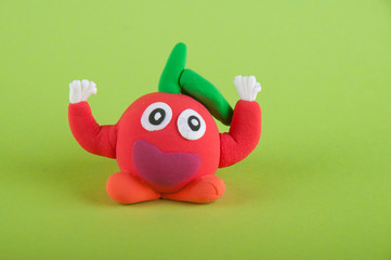 Red tomato with eyes, hands, leaf made of playing clay