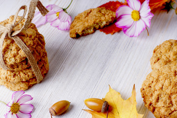Frame for text about autumn. Fallen leaves of red and yellow flowers are spread out along the edges along with cookies and flowers.