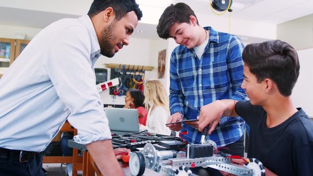 High School Teacher With Male Pupils Building Robotic Vehicle In Science Lesson