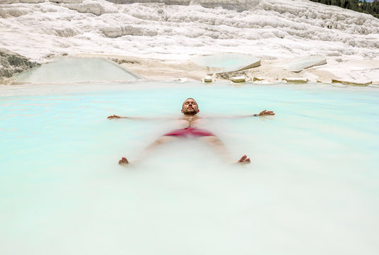 A man swims in the pool of thermal springs and travertine Pamukkale