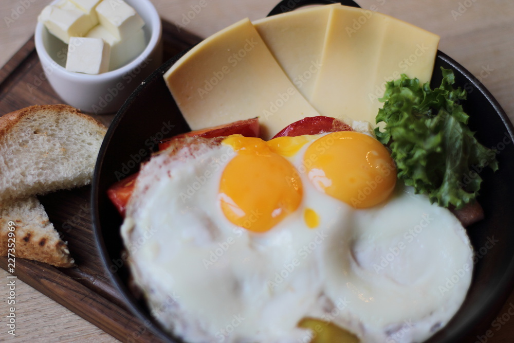 Wall mural eggs with cheese salad bacon and butter in small pan