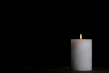 White burning candle on black background