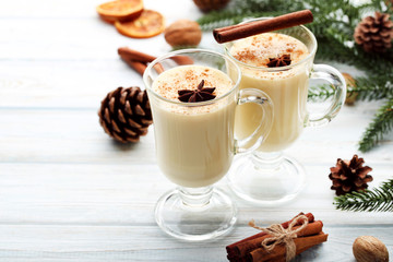 Eggnog in glasses with cinamon and star anise on wooden table