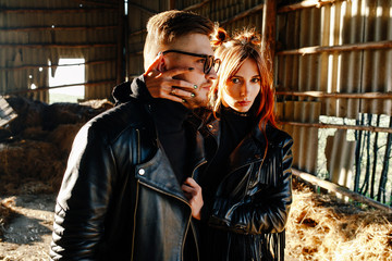 Fototapeta na wymiar bearded guy hugging with a red-haired girl at sunset. Loving Couple dressed in leather jackets