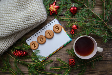 Christmas picture with the number 2019 on round cookies with a cup of tea on a wooden background