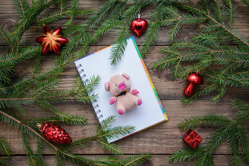 New Year picture with Christmas tree branches and symbol of 2019 - pink pig on a wooden background