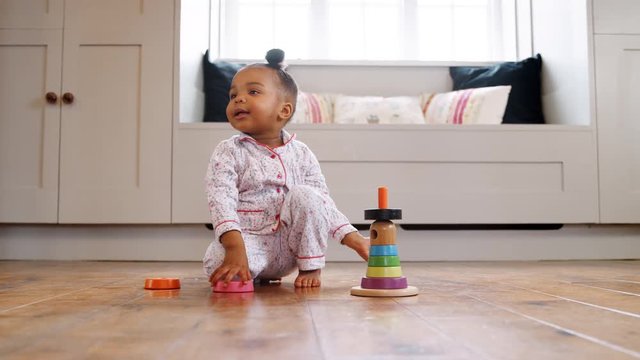 Smiling Female Toddler At Home Playing With Wooden Stacking Toy