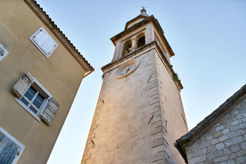 Fototapeta na wymiar Church tower with clock on facade in Budva in Montenegro