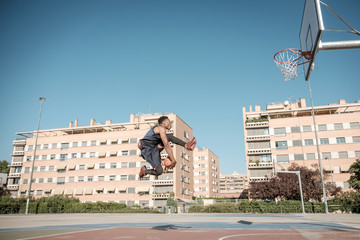 Afroamerican young man playing street basketball in the park