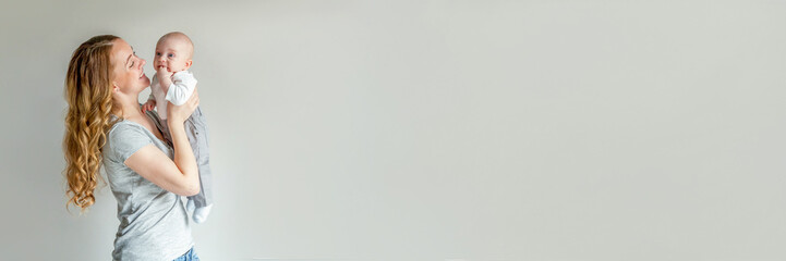 Mother holding her newborn child. Woman and infant boy relax and playing on white background. Mom...