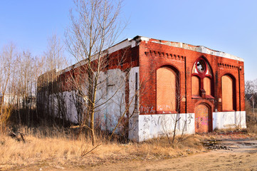 Fototapeta na wymiar Stara, zniszczona, opuszczona fabryka wśród jesiennych drzew w słoneczny dzień.