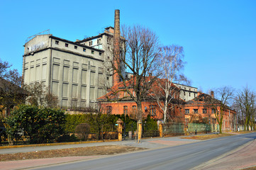 Fototapeta na wymiar Stara, zniszczona, opuszczona fabryka wśród jesiennych drzew w słoneczny dzień.