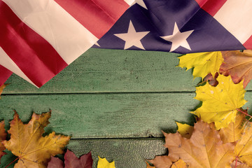 Green vintage wooden background covered with american flag and autumn leaves, copy space