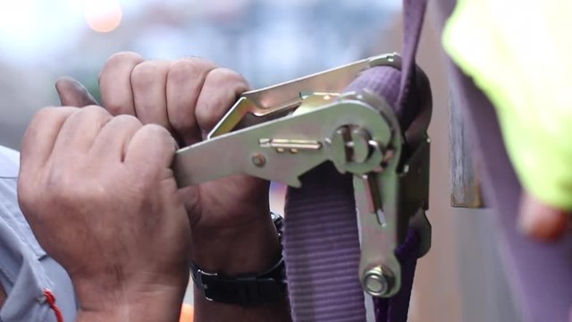 Attaching cargo with strap. Worker securing cargo transportation with strap6
