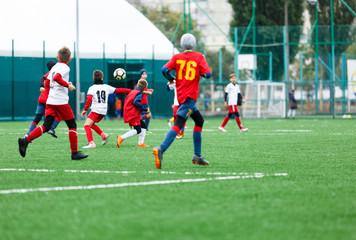 football teams - boys in red, blue, white uniform play soccer on the green field. boys dribbling. dribbling skills. Team game, training, active lifestyle, hobby, sport for kids concept