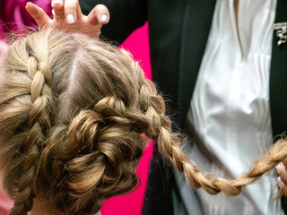 Fototapeta premium Hairdresser. Creating hair. Braiding pigtails. Blonde girl with pigtails.