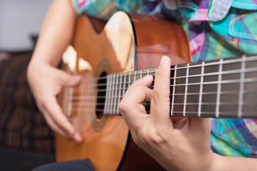 Obraz premium Bearded hipster man hand playing acoustic guitar. Close-up selective focus on hand.