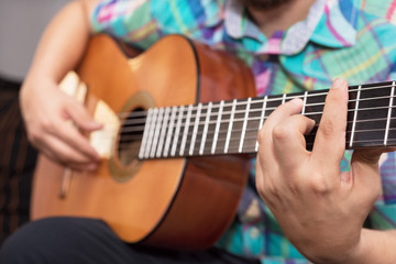 Fototapeta premium Bearded hipster man hand playing acoustic guitar. Close-up selective focus on hand.