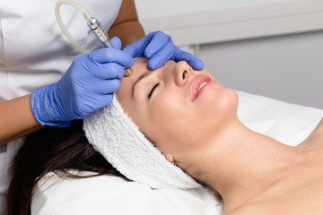 Beautiful woman getting facial microdermabrasion peeling treatment at luxury cosmetic beauty spa clinic. Exfoliation, rejuvenation and hydratation. Cosmetology concept.