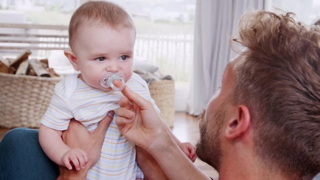 Over shoulder view of dad giving young toddler pacifier