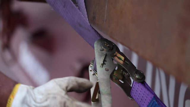 Construction worker detaching rope. Removing cargo strap