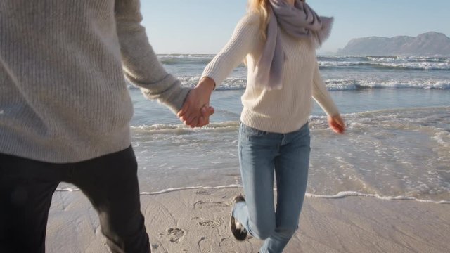 Couple Having Fun Running Along Winter Beach Together