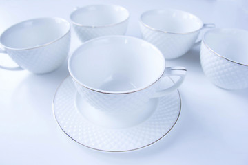 White empty porcelain tea set: cups and small plates at white background