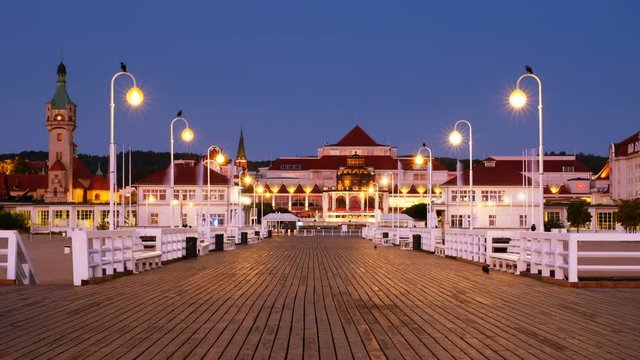 Sopot, Poland. A sunrise time-lapse of a long wooden pier in Sopot, Poland, with a view of the lighthouse and other old town signature buildings. Zoom in