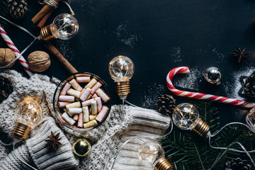 Christmas flat lay. Chocolate or cocoa with marshmallow, cookies, candy and the garland on a dark background. 