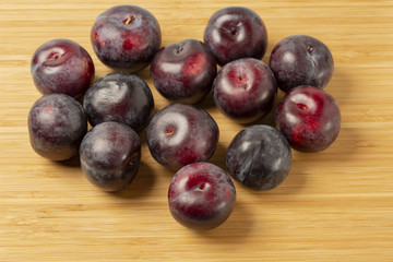 Red plum fruits close up view isolated on wooden background. Fruits concept. Health concept. Beautiful backgrounds.