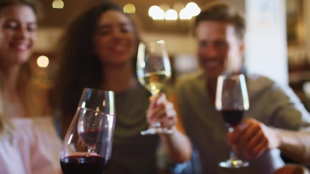 Young adults making a toast with wine, focus on glasses