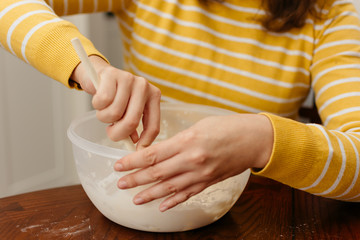 Woman hands mixing bread dough on wooden table