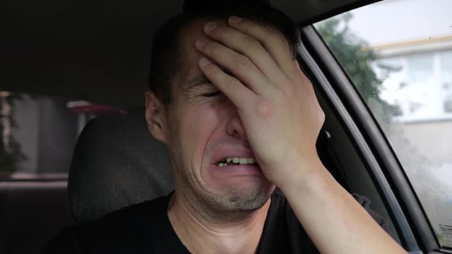 Sad desperate man crying in the car