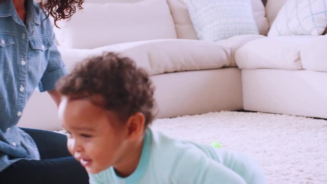 Black toddler boy crawling around his kneeling young mother