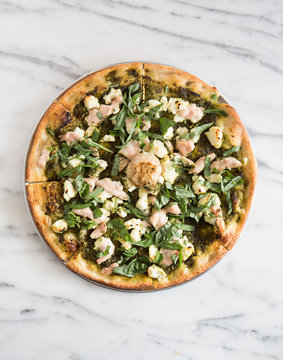 WHole pizza on a dish over marble surface.