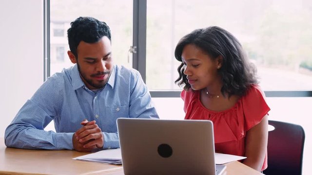 High School Tutor Giving Female Student One To One Tuition At Desk 