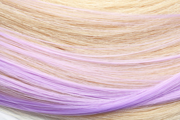 Strands of blond and violet hair as background, closeup