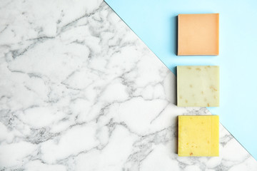 Different handmade soap bars and space for text on marble table, top view