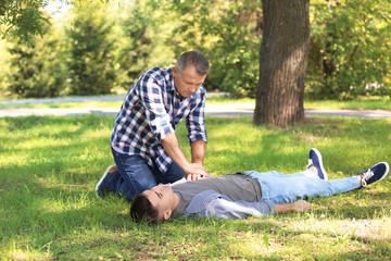 Naklejka na ściany i meble Passerby performing CPR on unconscious man outdoors. First aid
