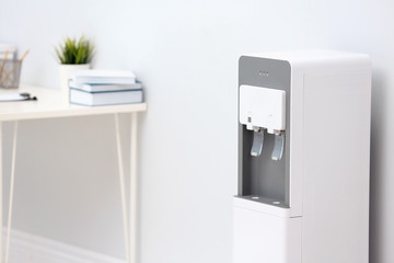 Modern water cooler near light wall in office