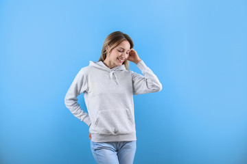 Portrait of woman in hoodie sweater on color background. Space for design