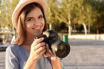 Young female photographer with professional camera on street. Space for text