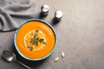 Flat lay composition with bowl of pumpkin soup and space for text on gray background
