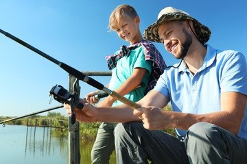 Father and son fishing together on sunny day