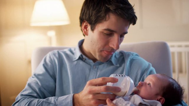 Father In Nursery Feeding Baby Son From Bottle